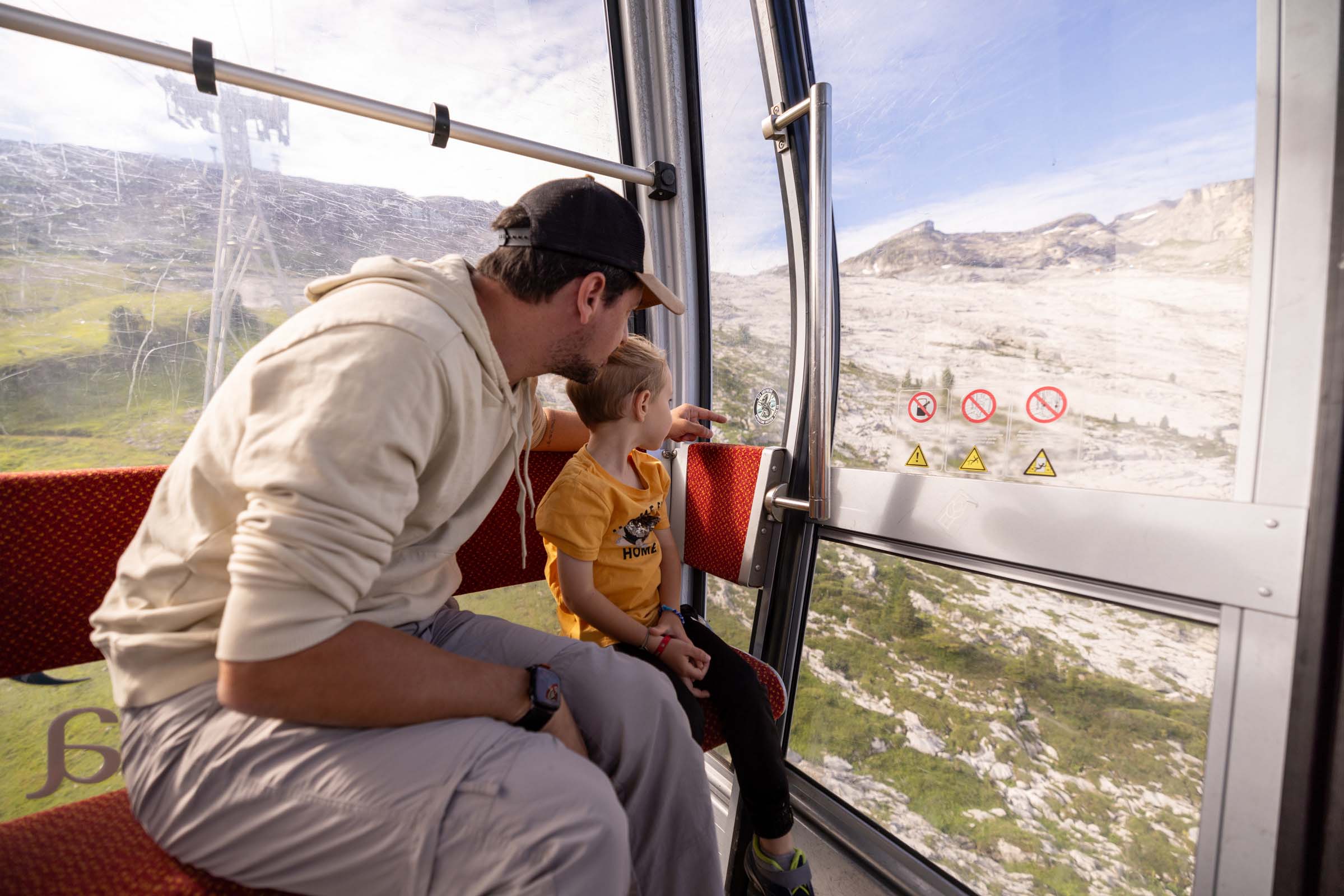 A father and son in a cable car above the Désert de Platé