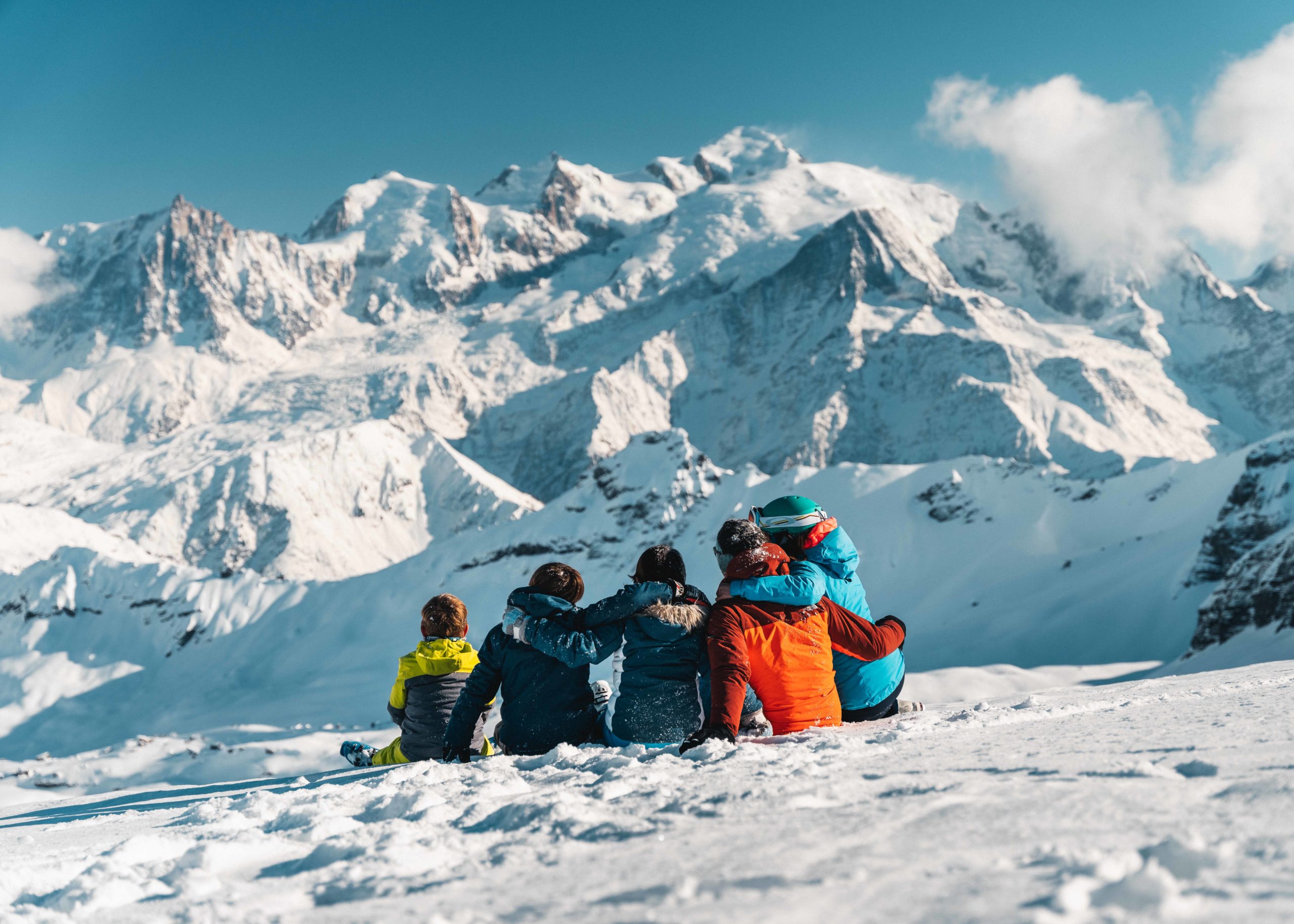 Gezin zittend in de sneeuw met uitzicht op de Mont Blanc in Flaine