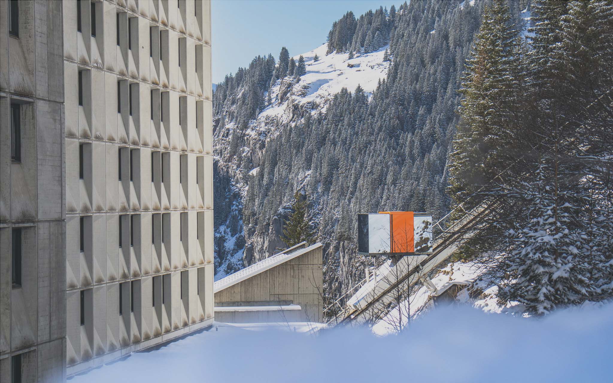 Orange outdoor lift linking two floors of Flaine resort in winter