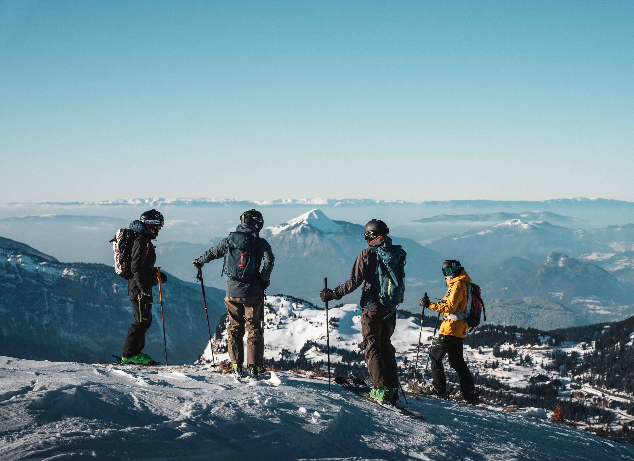 Flaine- Vier skiërs op een besneeuwde helling met de Cluses vallei en de berg Le Môle op de achtergrond.