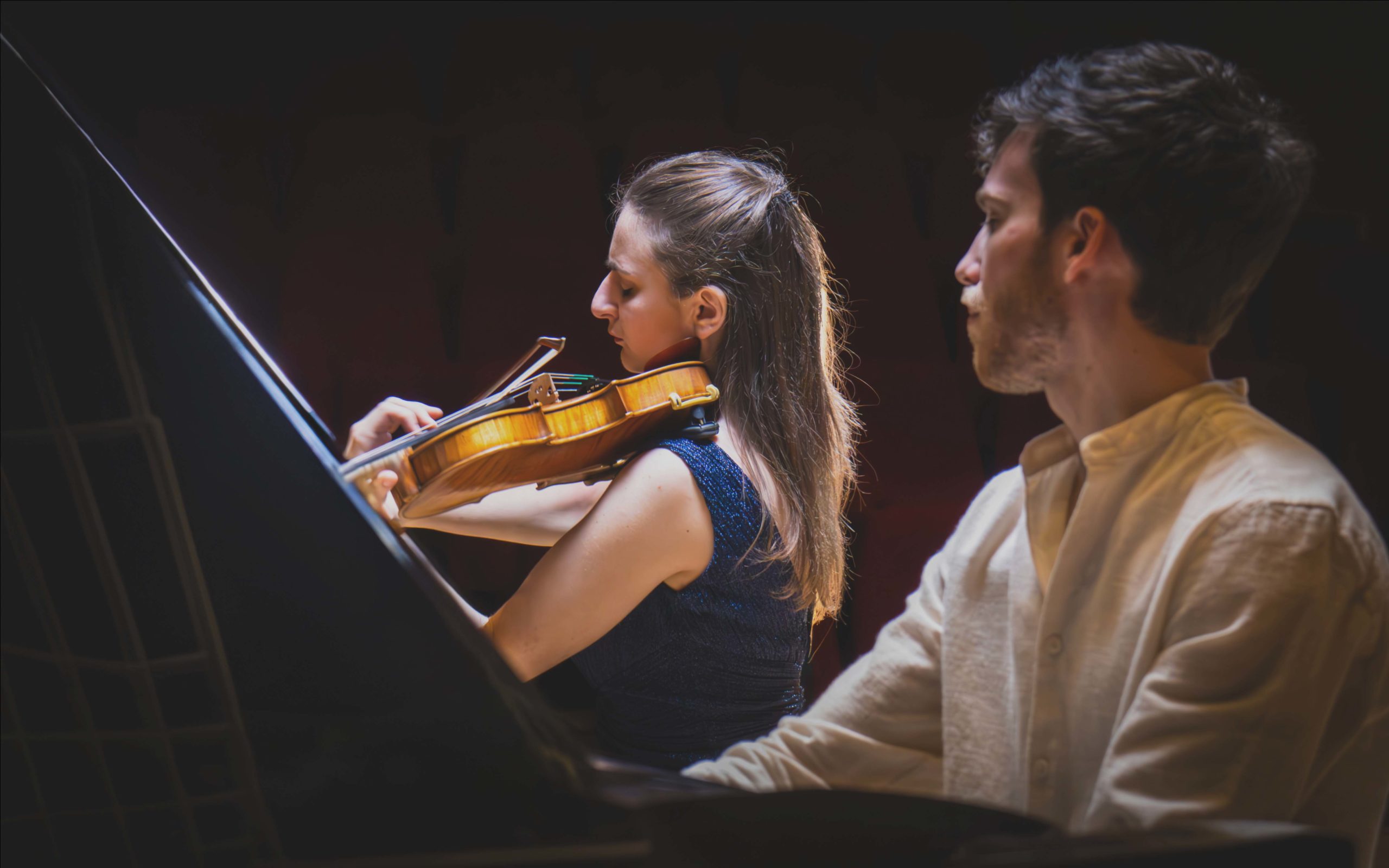 Close-up van een pianist en een violist, opgeleid aan muziekacademies, die klassieke muziek spelen in het auditorium van Sylvie en Éric Boissonnas in Flaine.