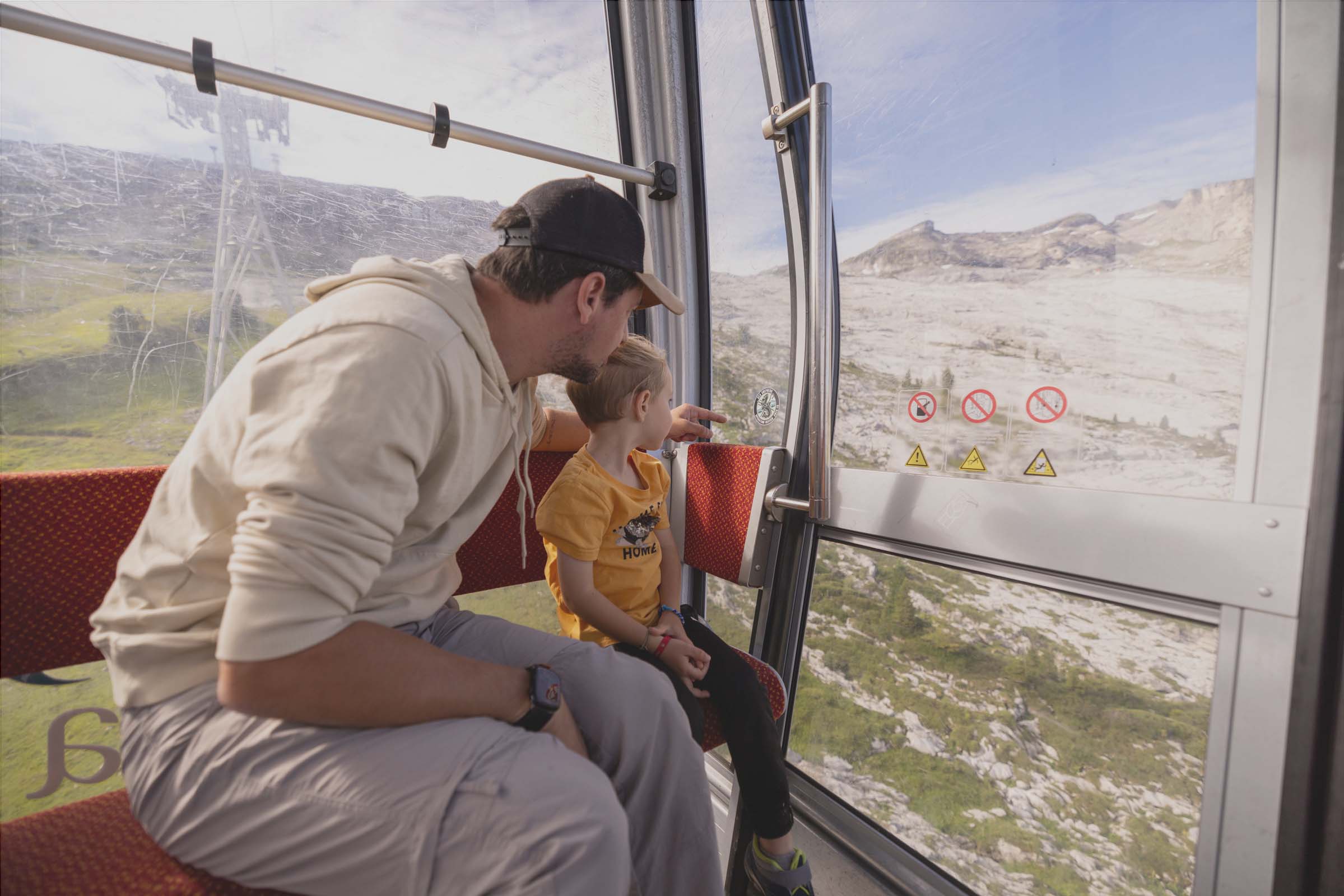 Flaine- A father and child sitting in the Grandes Platières cable car, looking out over the Flaine mountains towards the Platé desert and its lapiazs.