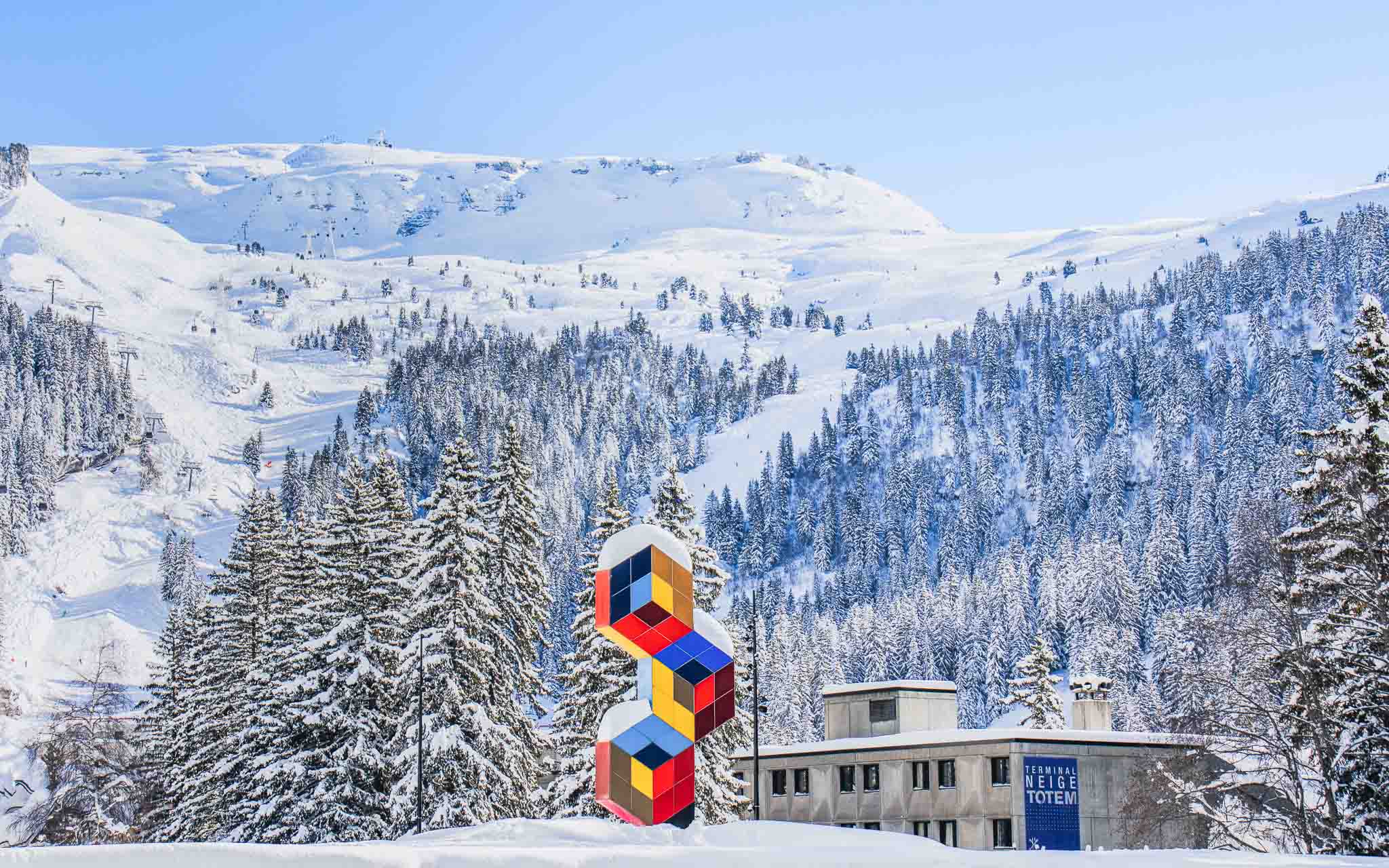 Photo of Victor Vasarely's colourful sculpture ‘Les Trois Hexagones’, surrounded by snow-capped mountains and forests in the resort of Flaine, Haute-Savoie.