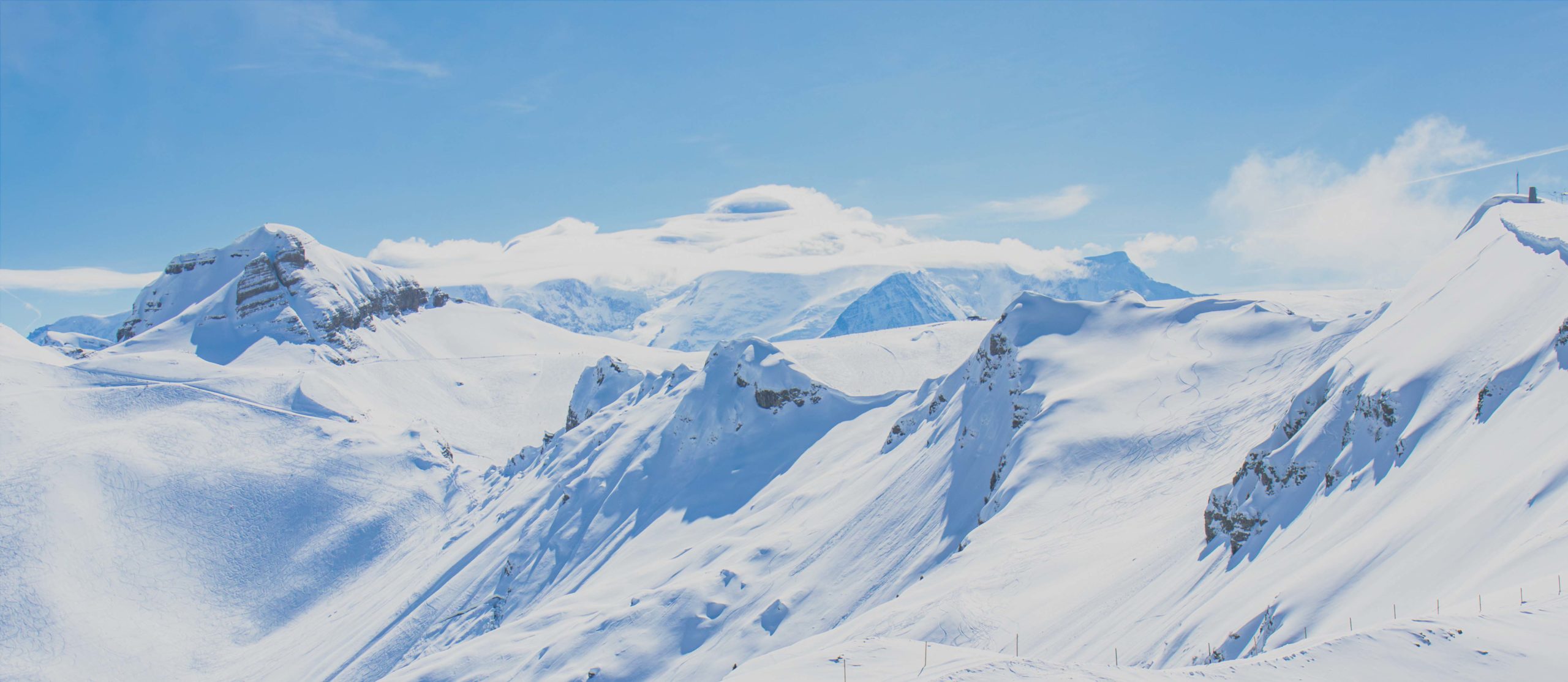 Vue panoramique du Mont Blanc et des montagnes enneigées environnantes depuis Flaine, sous un ciel bleu clair et lumineux.