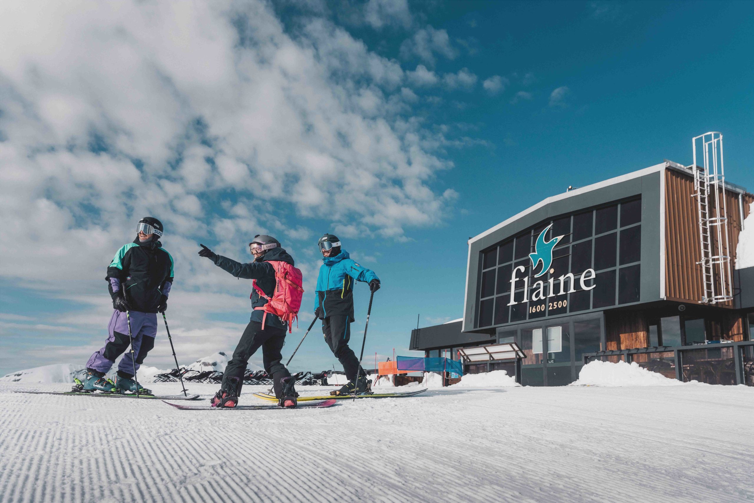 Flaine- deux skieurs et un snowboardeur devant la gare d'arrivée du téléphérique des Grandes Platières