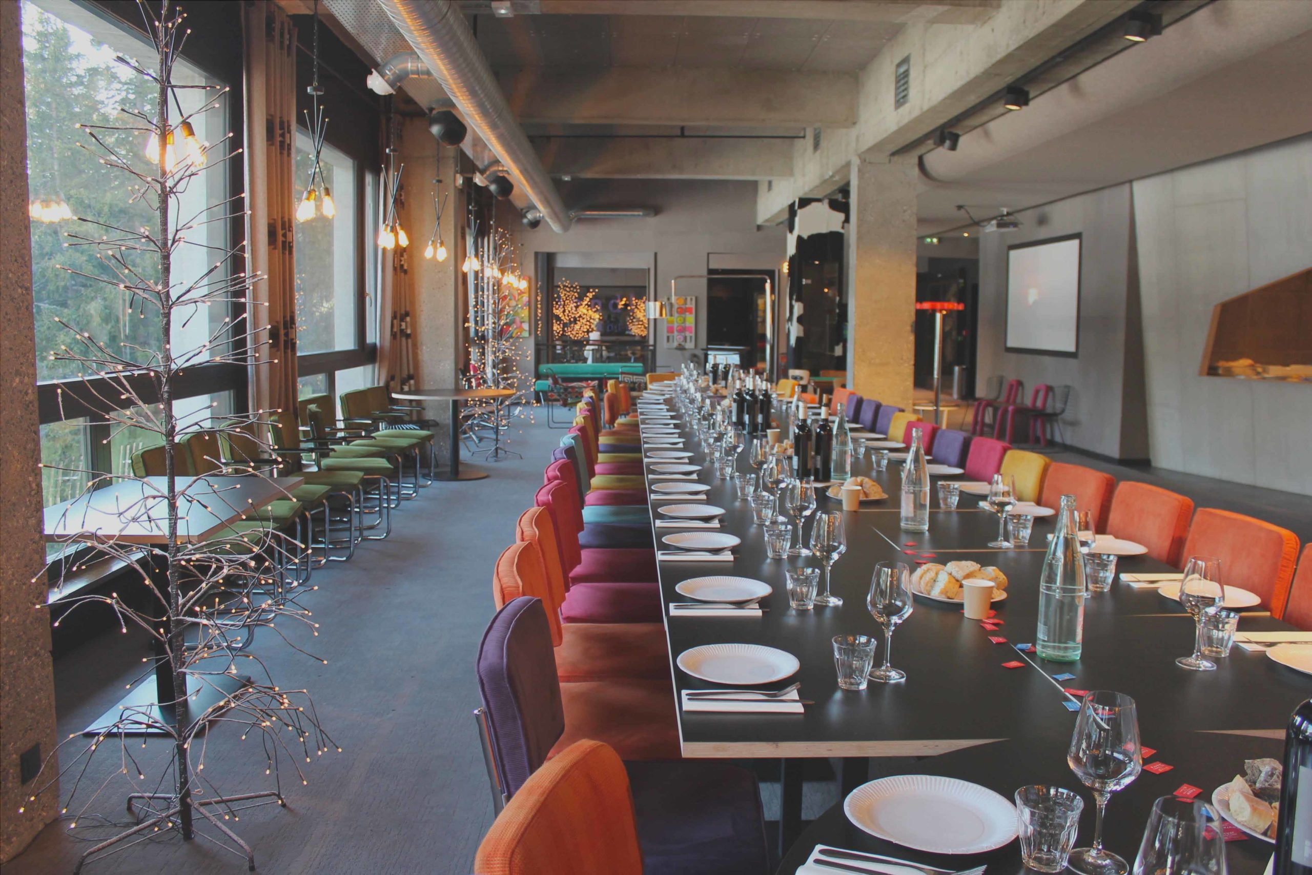 Elegant eetkamerinterieur van restaurant Le Totem, met een lange tafel en kleurrijke stoelen.