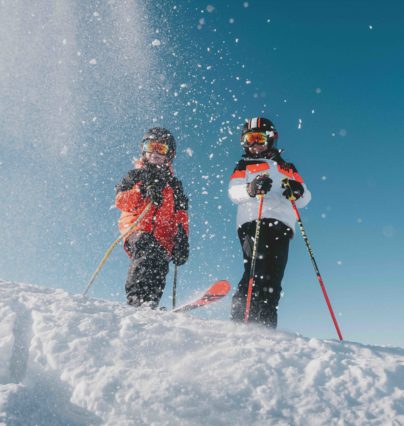 Flaine- Twee jonge skiërs op de top van een sneeuwjacht tegen een blauwe lucht.