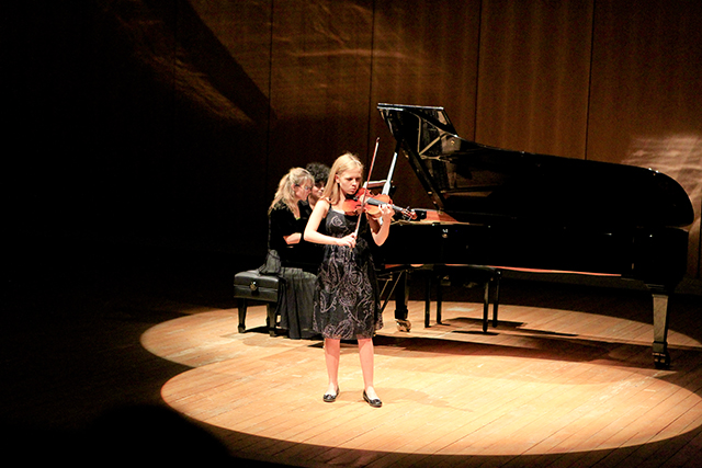 Jonge violist begeleid op de piano tijdens een klassiek muziekconcert in het Flaine auditorium in de zomer.