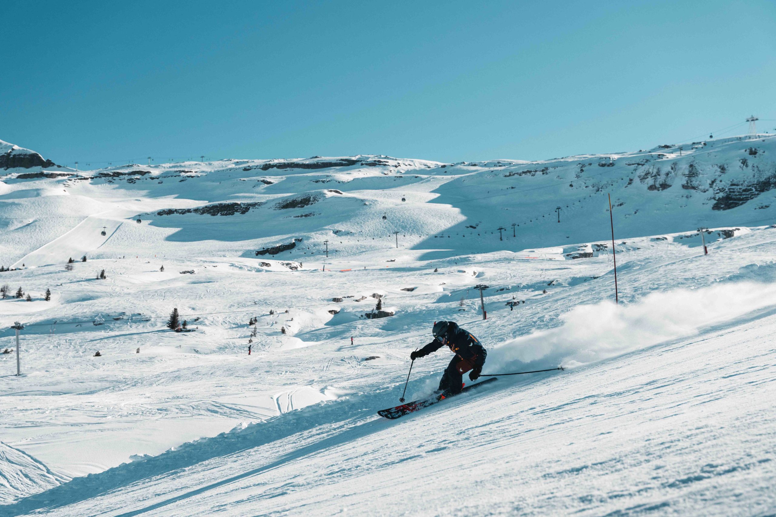 Skieur descendant une piste de ski avec le domaine skiable de Flaine en toile de fond