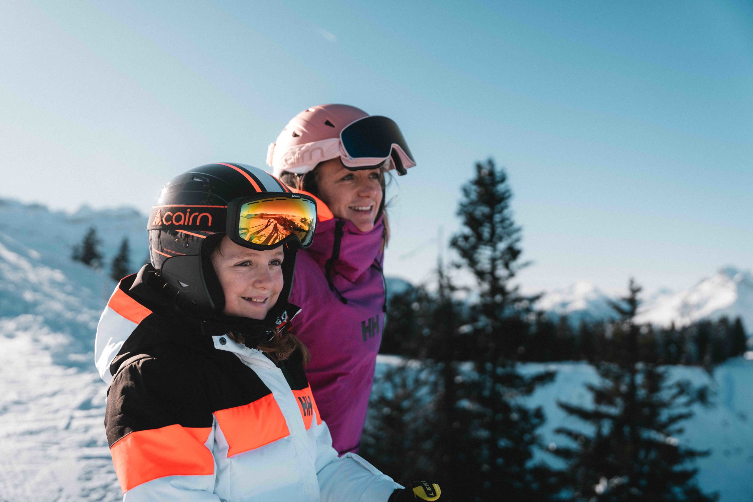 Lachende moeder en dochter in ski-uitrusting, genietend van een zonnige dag op de besneeuwde hellingen van Flaine.